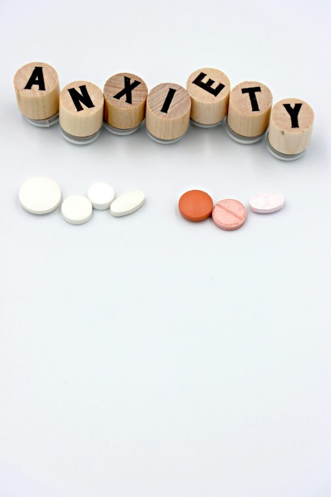 Image of anxiety pills and wooden blocks forming the word 'anxiety' on a white background.